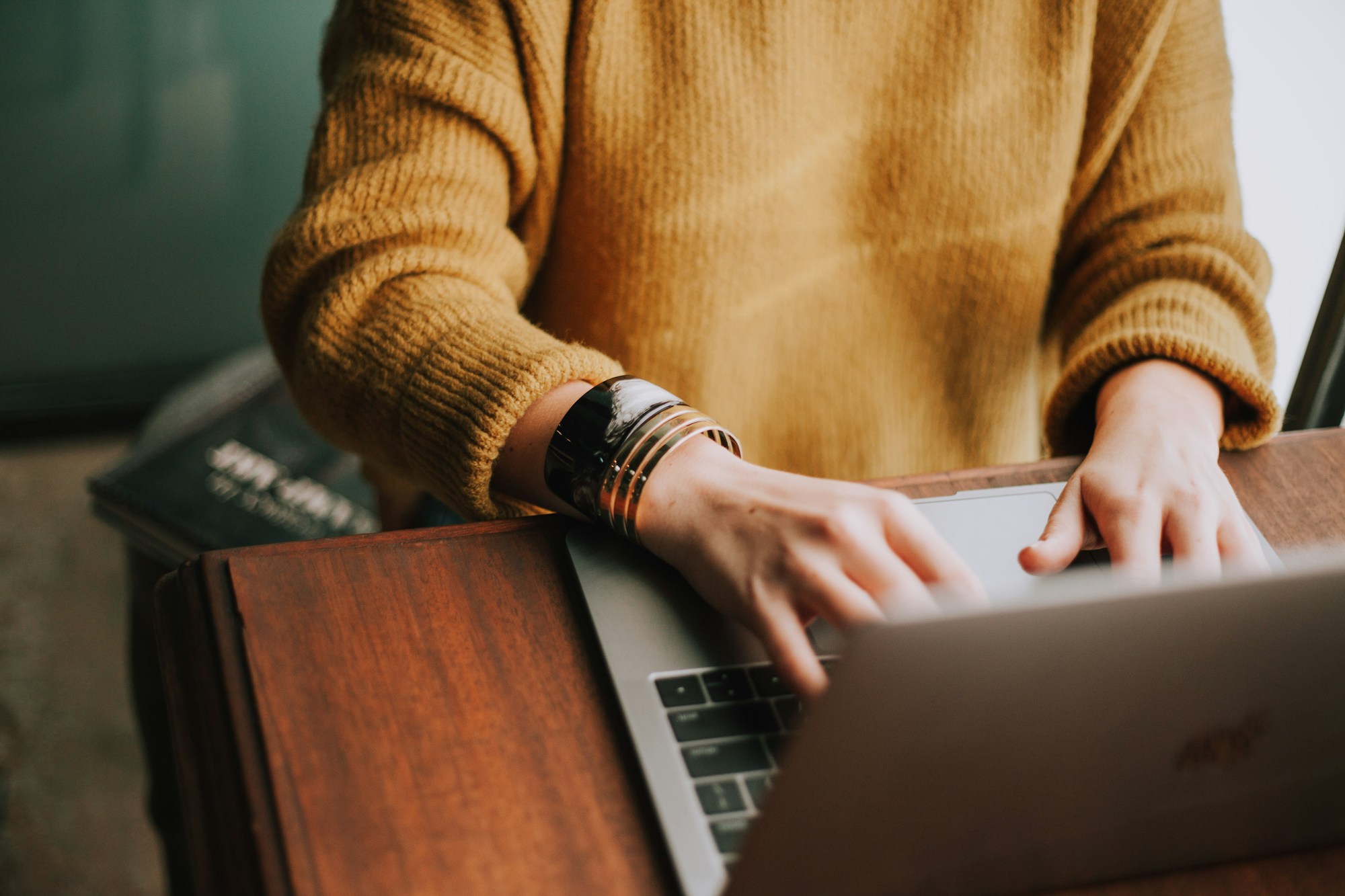 A person taking notes beside a laptop